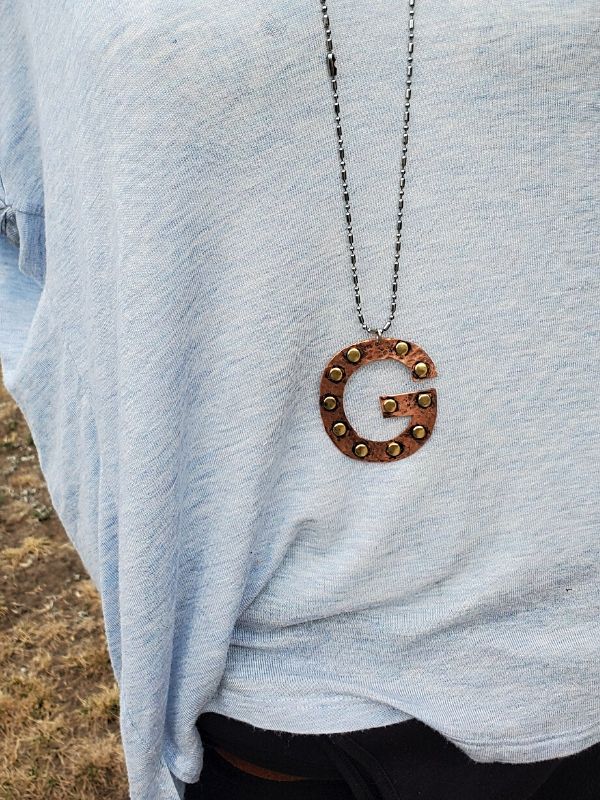 big letter g necklace on mannequin with blue top